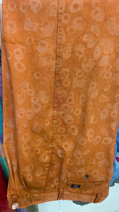 A pair of vintage Dockers pants in a gold brown color, with a pattern of beeswax batiked designs creating a geometric motif.